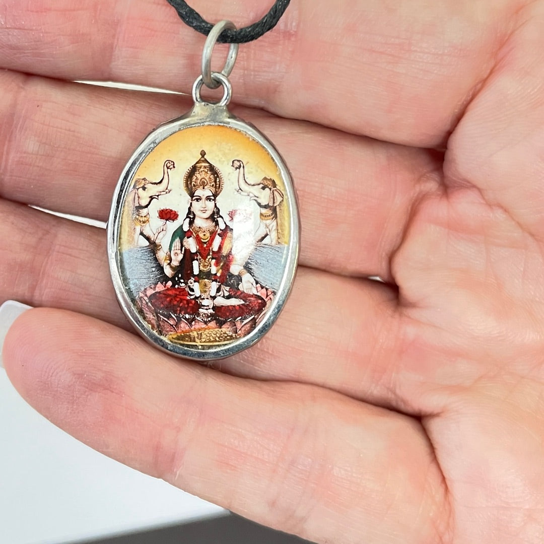 Lakshmi ceramic pendant shown for scale held in a hand