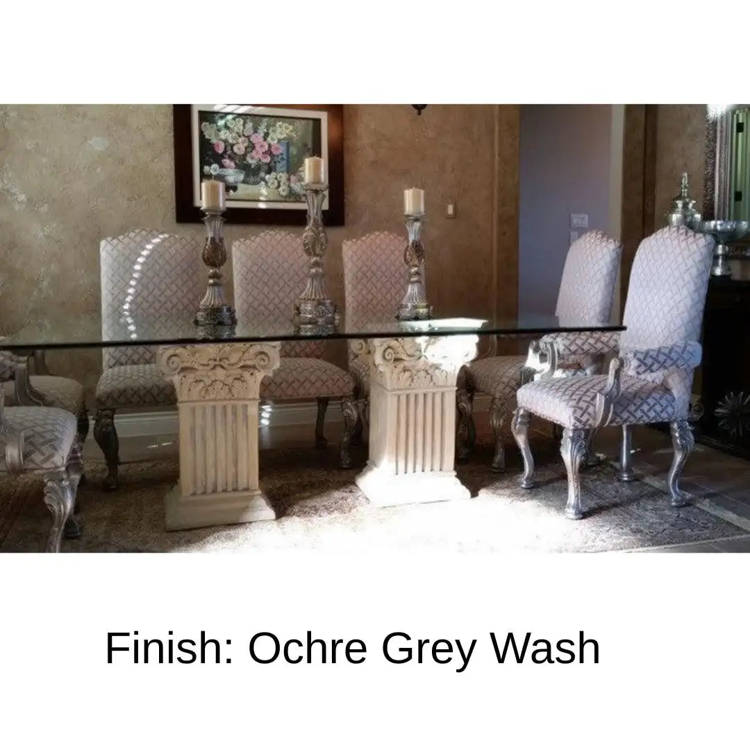 Pair of square fluted Corinthian table bases supporting a large rectangular glass dining table in a spacious interior, demonstrating classical architectural furniture used for formal dining and entertaining in a real home