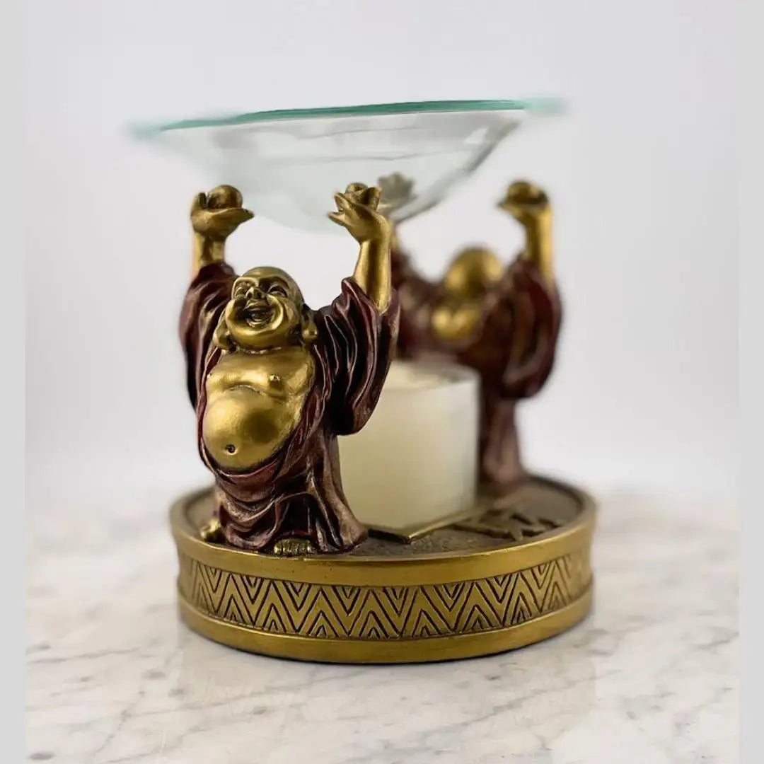 Happy Buddha oil burner with gold and bronze finish on marble surface