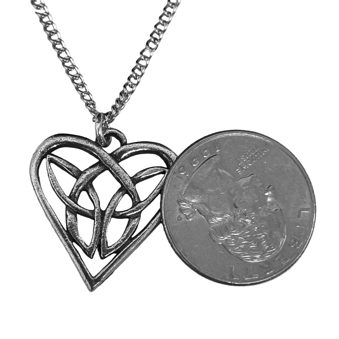 Pewter heart-shaped pendant with Celtic knot design next to a quarter for scale