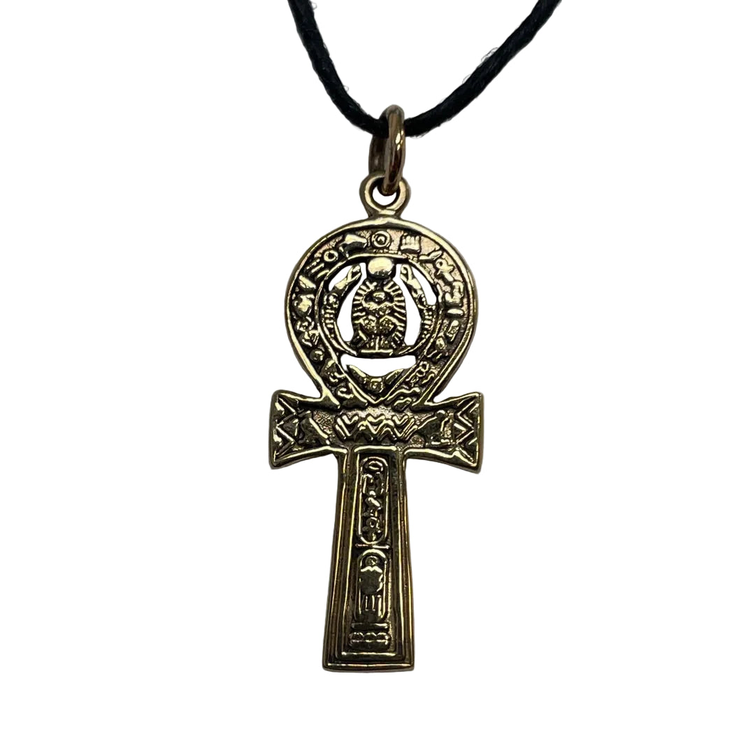 An ancient Egyptian Ankh pendant in an antique gold finish, hanging from a black cord on a neutral gray background.