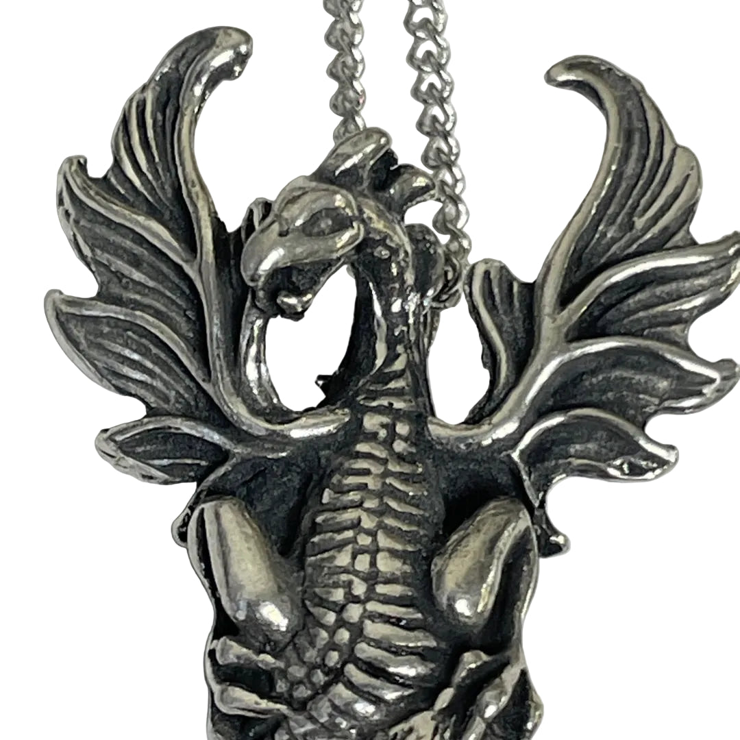 A close-up of a silver dragon pendant necklace on a matching chain, set against a plain light gray background.