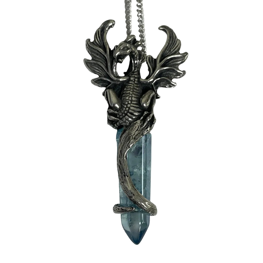 A silver-toned dragon pendant with spread wings wrapping around a pointed light blue crystal point, hanging from a silver chain against a plain light background.