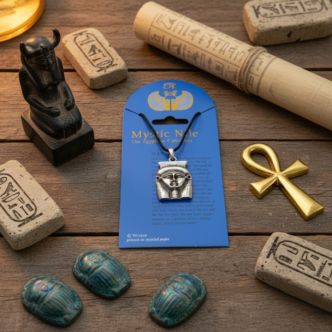 A silver-toned Egyptian Hathor pendant necklace on a black cord, displayed around egyptian cuneiform items
