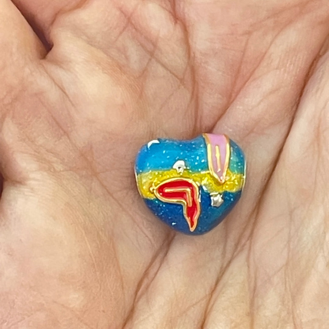 Close-up of S925 silver charm with enamel melting time design for scale in a hand
