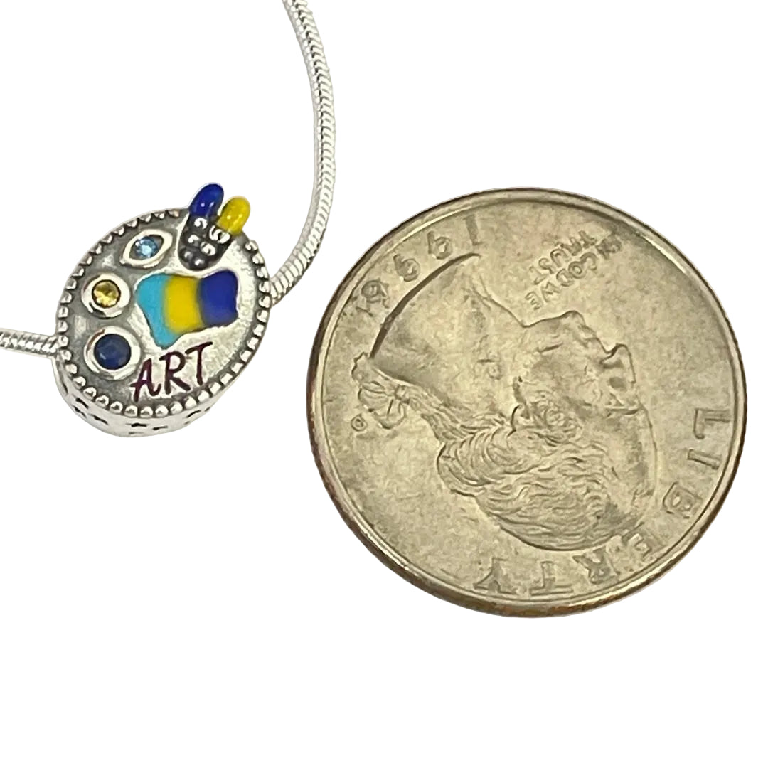 Painter palette charm positioned next to coin for size comparison