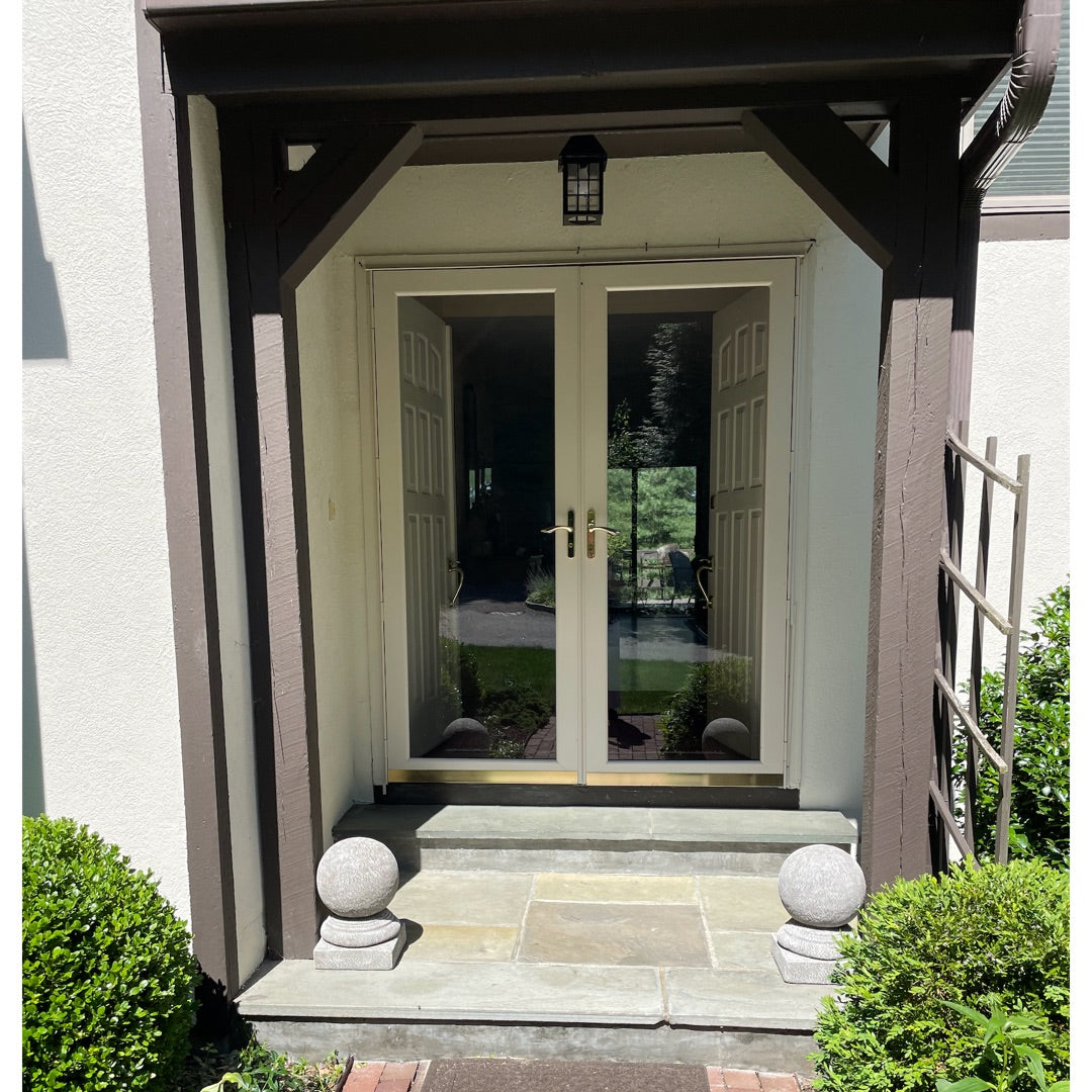 Front door of a house with two round orb garden finials to flank the entrance steps.