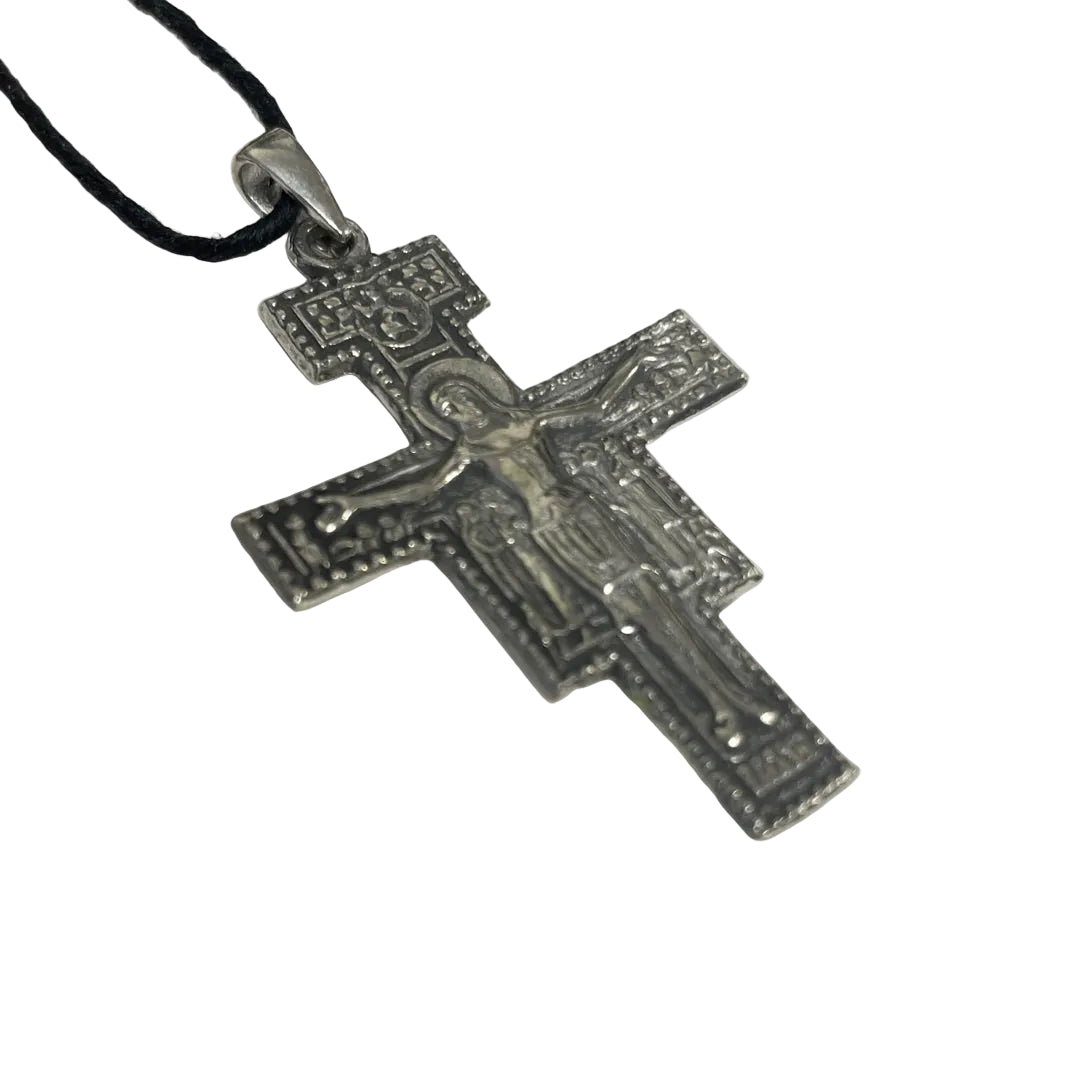 An ornate silver-toned Orthodox Christian cross pendant with a detailed figure of Jesus Christ, hanging from a black cord on a plain white background.