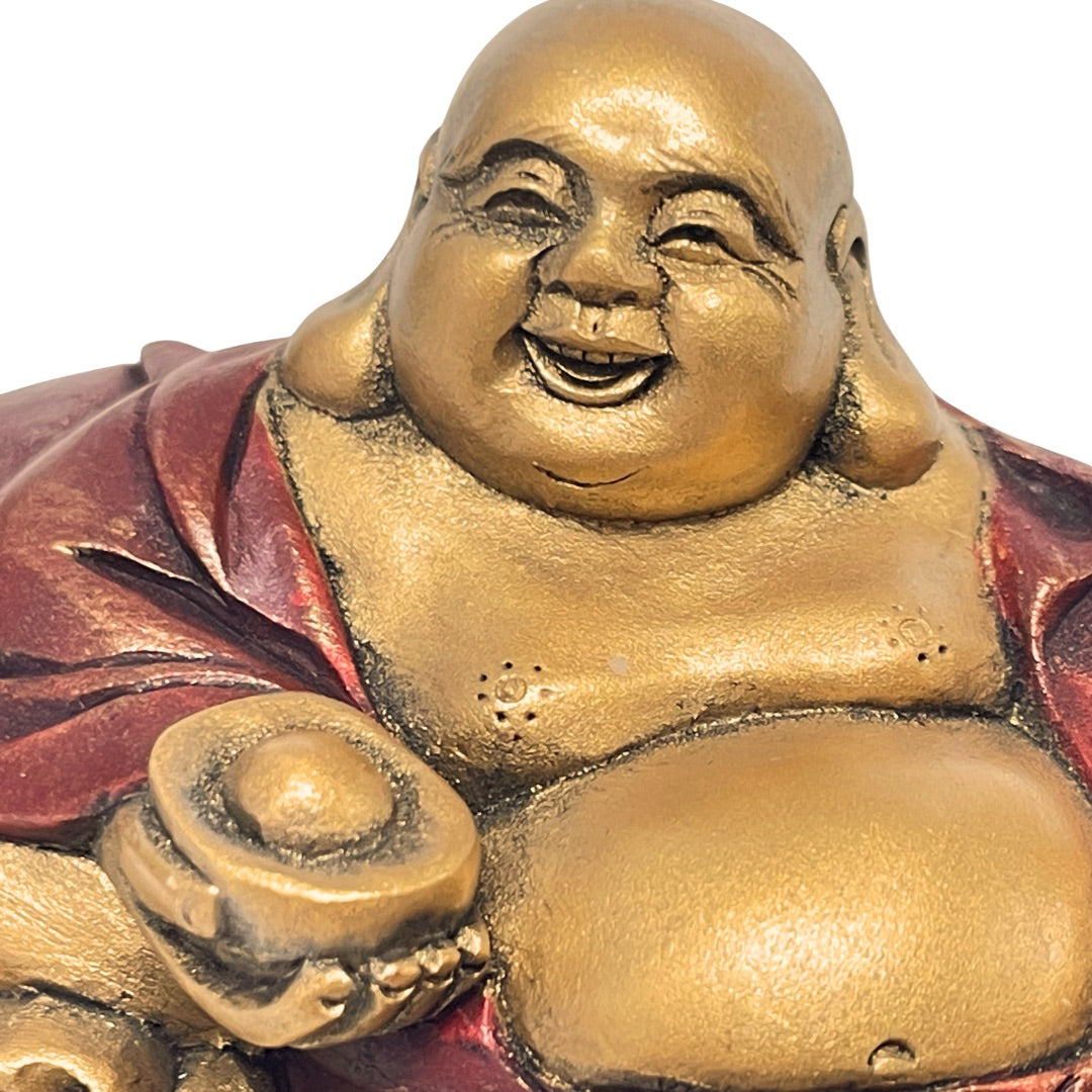 Close view of Budai's laughing face on the gold resin Happy Buddha statue