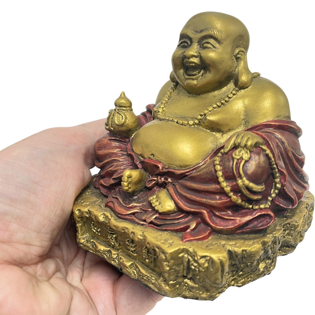 Hand holding for scale Ho Tai with a big open grin in antique gold and red