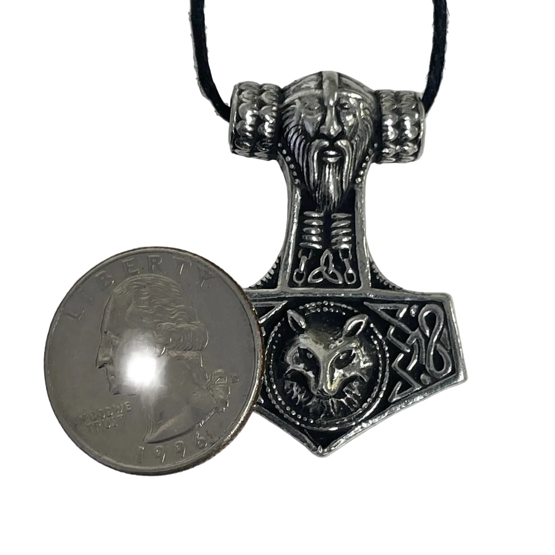 An ornate silver-toned metal pendant necklace with a ram's head and wolf motif, shown next to a US quarter for scale on a plain light background.