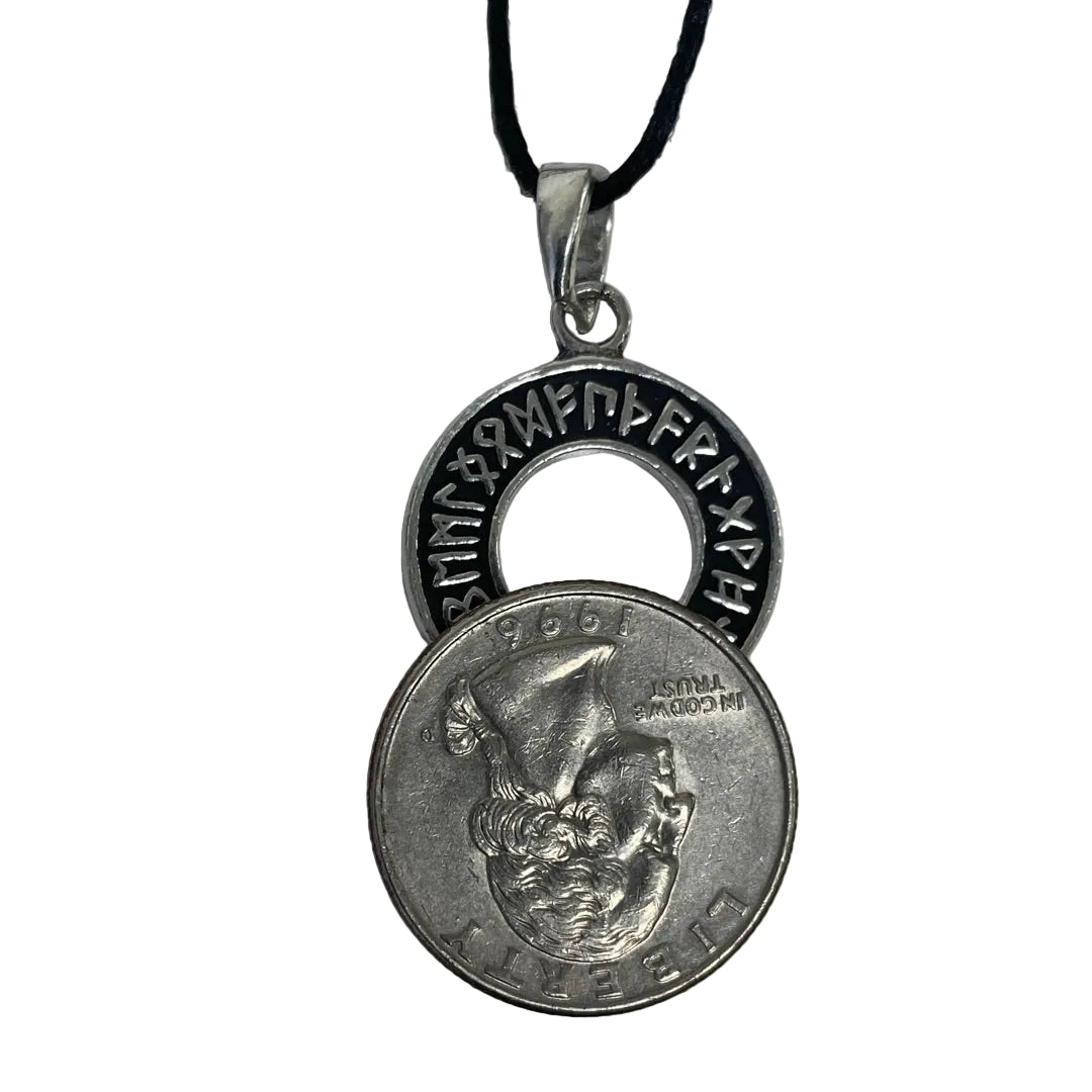 A silver-toned pendant necklace featuring a circular ring with engraved runes and a coin-penchant charm layered over a U.S.