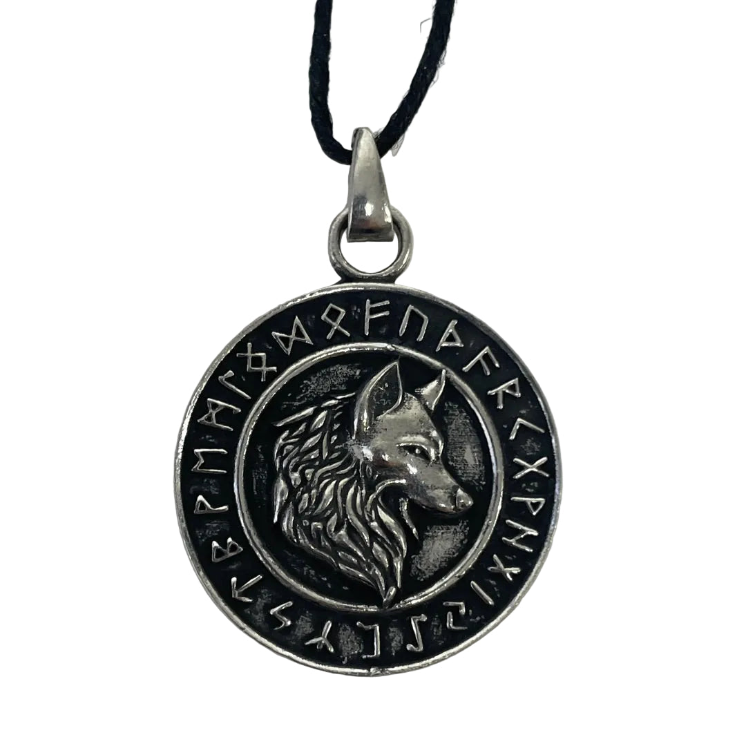 A circular silver-toned pendant necklace featuring an embossed wolf head in the center and runic symbols around the border, suspended from a black cord on a plain light background.