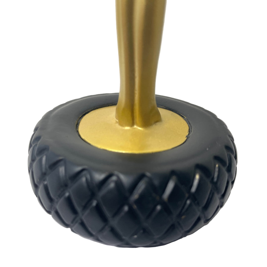 Detail view of the statue’s base with gold figure and black tire design, licensed reproduction from the Gala–Salvador Dalí Foundation