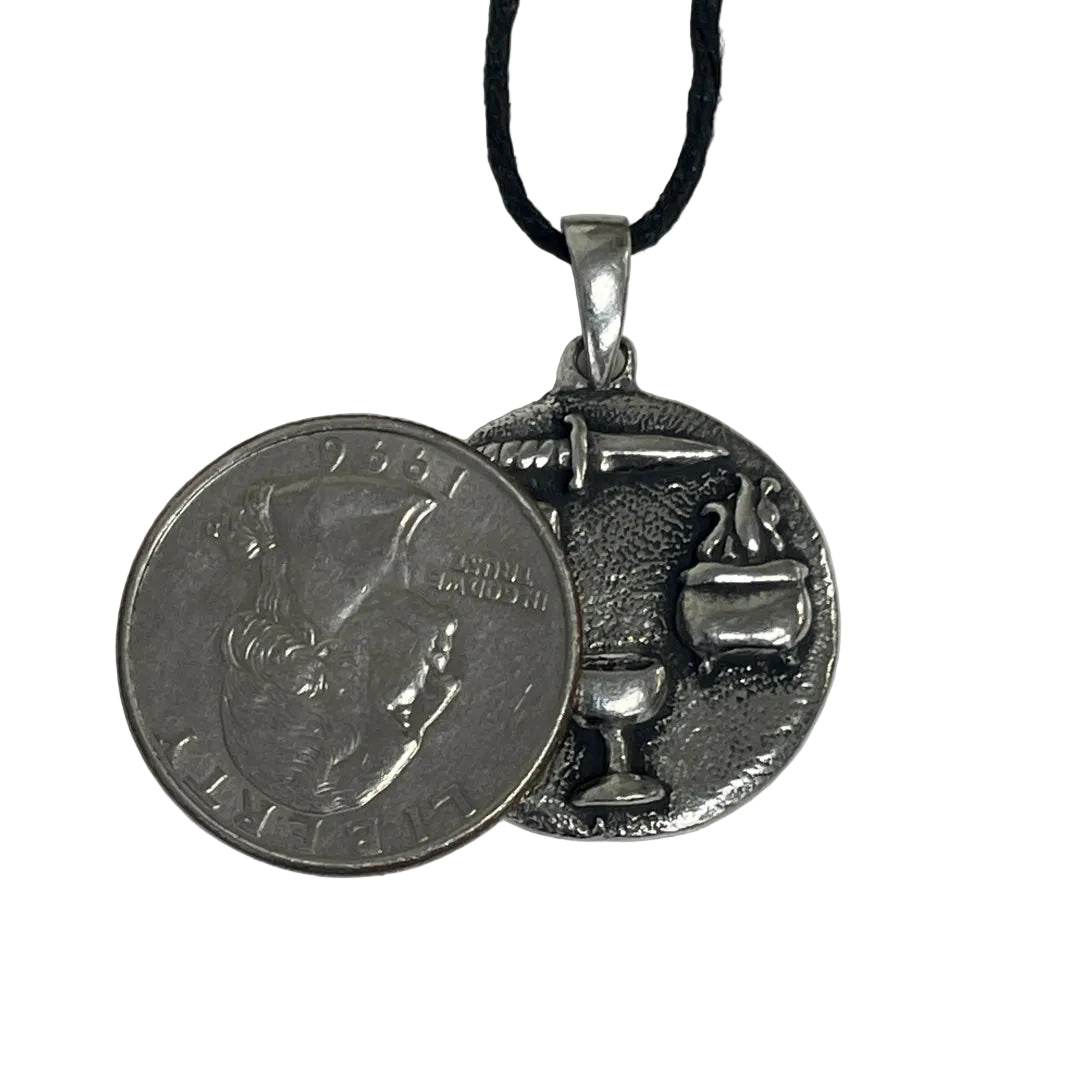 Wiccan necklace with tools of wiccan practice next to a quarter for scale